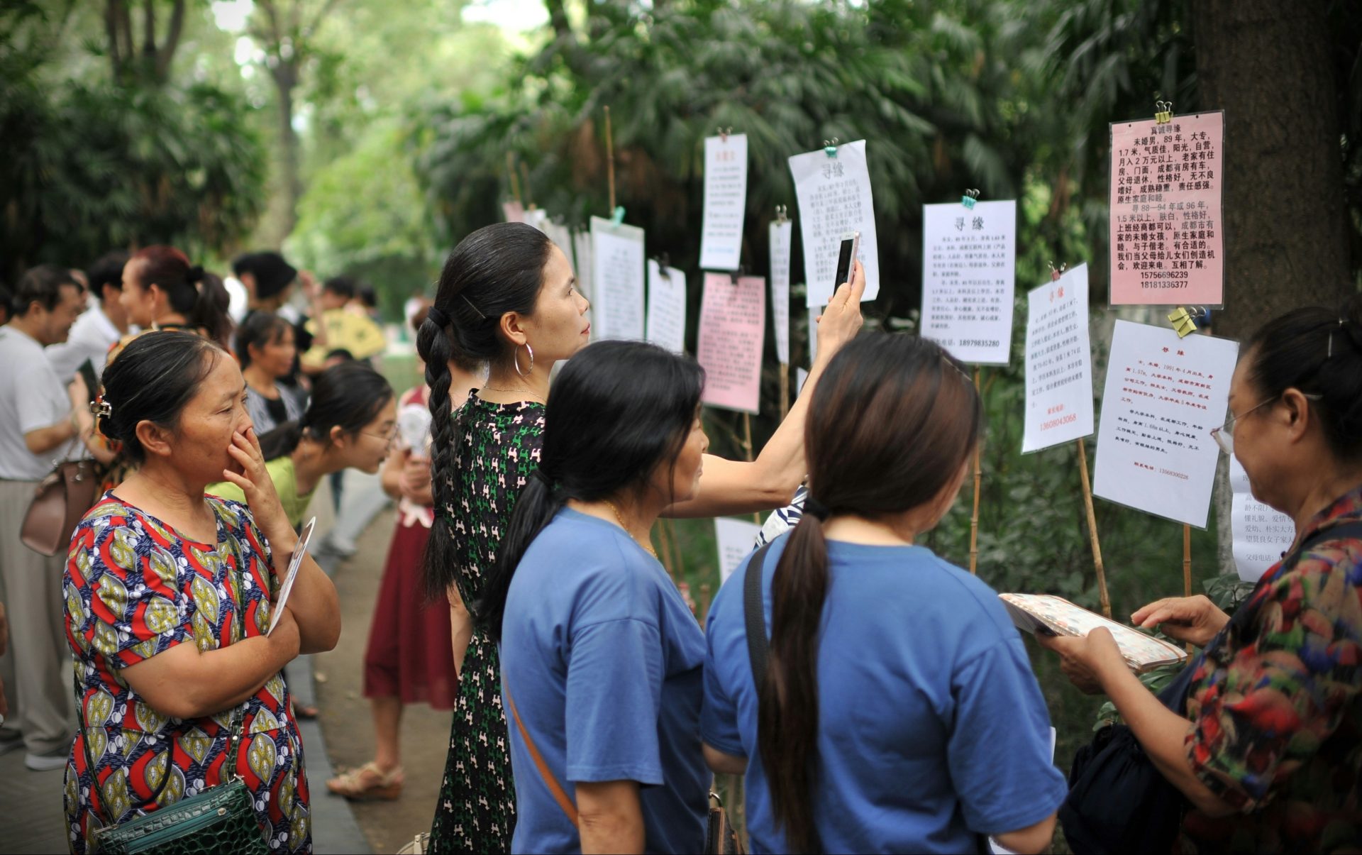 People gather to read notices posted outdoors.